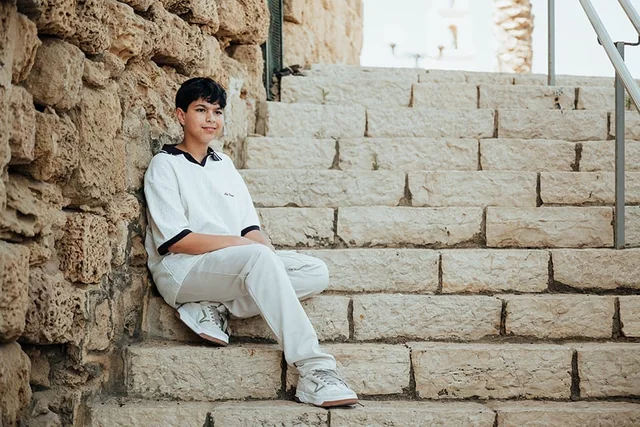 איתן יושב על מדרגות אבן בצילומי בר המצווה